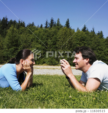 Man taking photograph of girlfriend in grass 11630515