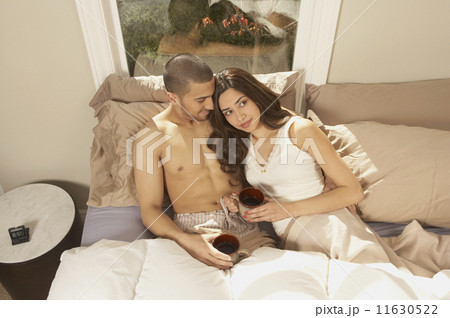 Hispanic couple drinking coffee in bed  11630522