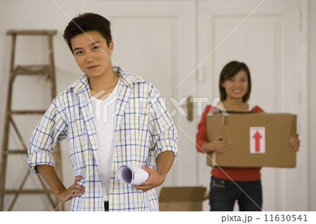 Asian couple with blueprints in new house 11630541