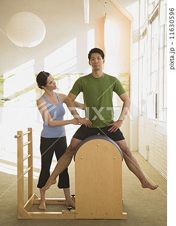 Instructor helping man in exercise studio Instructor helping man in exercise studio 11630596