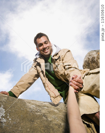 Pacific Islander man helping person climb 11630610