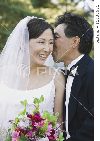 Asian groom telling secret to bride 11630631