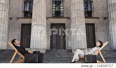 Businesspeople in lounge chairs in front of building 11630727