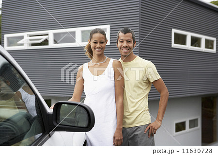 Multi-ethnic couple standing next to car 11630728