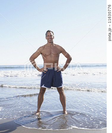 Full view of man standing with hands on hips at the beach 11630776