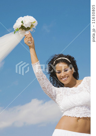 Hispanic bride holding bouquet over head Hispanic bride holding bouquet over head 11630805