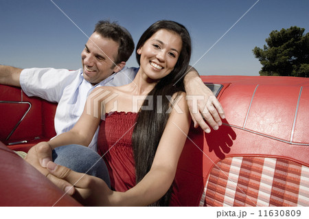 Multi-ethnic couple in backseat of convertible Multi-ethnic couple in backseat of convertible 11630809
