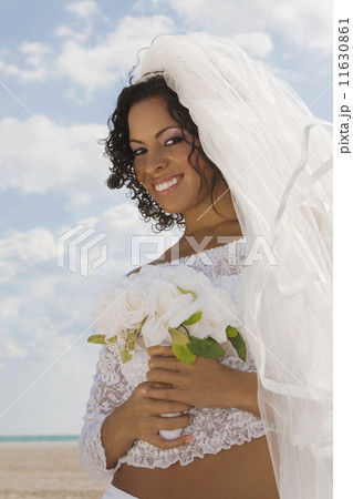 Hispanic bride holding bouquet 11630861