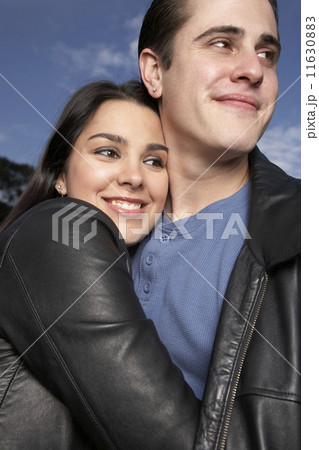 Multi-ethnic couple hugging outdoors 11630883
