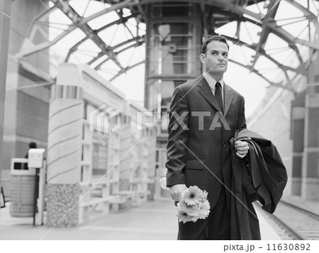 Man holding flowers and waiting at train station 11630892