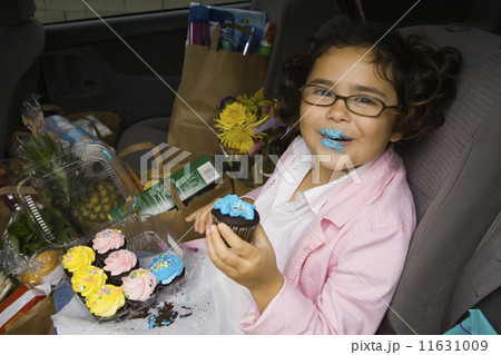 Girl sitting in backseat of car eating with groceries 11631009