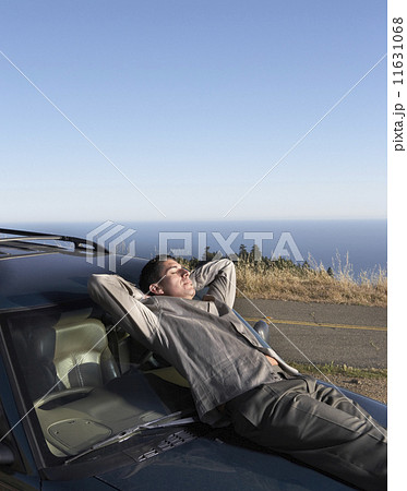 Male driver resting on his car hood Male driver resting on his car hood 11631068