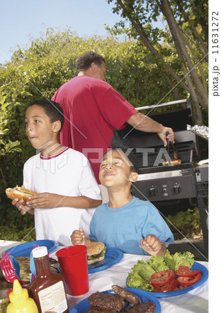 Boys eating hamburgers at backyard barbecue Boys eating hamburgers at backyard barbecue 11631272