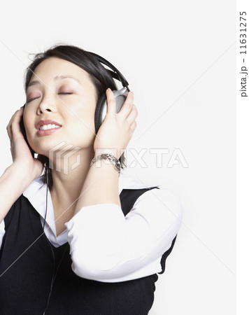 Studio shot of Asian woman listening to music with headphones Studio shot of Asian woman listening to music with headphones 11631275