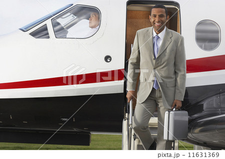 Mixed Race businessman exiting airplane Mixed Race businessman exiting airplane 11631369