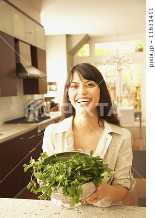 Hispanic woman holding vegetables in colander Hispanic woman holding vegetables in colander 11631411