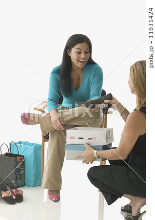 Sales clerk assisting teen girl buying shoes 11631424