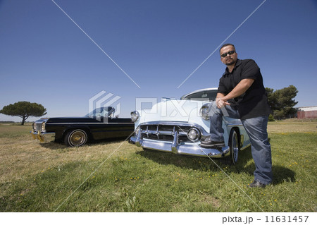 Hispanic man leaning on low rider car 11631457