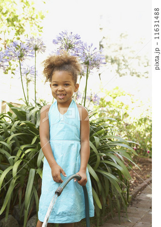 Mixed Race girl holding garden hose 11631488