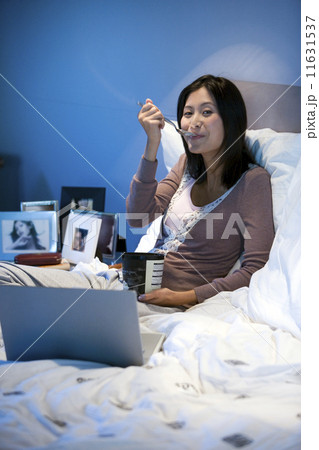 Asian woman eating ice cream in bed Asian woman eating ice cream in bed 11631537
