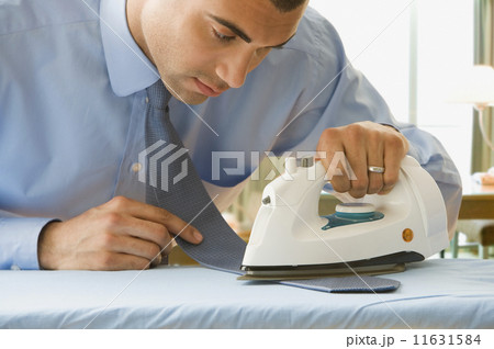 Hispanic businessman ironing necktie 11631584