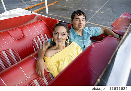 Hispanic couple sitting in convertible 11631625