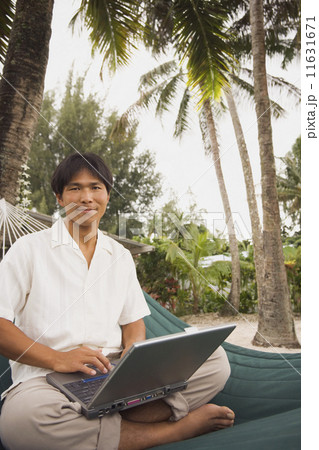 Asian man with laptop in hammock 11631671