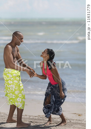 Multi-ethnic couple holding hands at beach 11631779