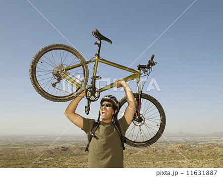 Hispanic man holding bicycle over head Hispanic man holding bicycle over head 11631887