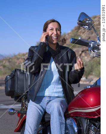 Hispanic woman on motorcycle talking on cell phone 11631991