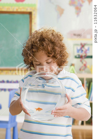 Mixed Race boy looking at fish in bowl 11632064