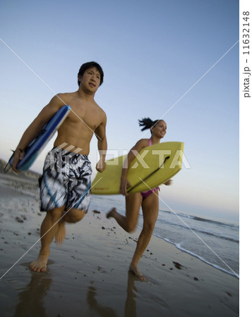 Multi-ethnic couple running with surfboards Multi-ethnic couple running with surfboards 11632148