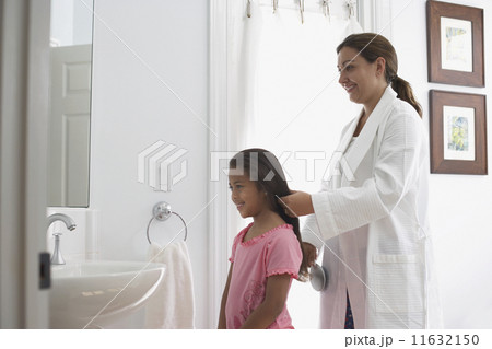 Mother brushing daughter's hair 11632150