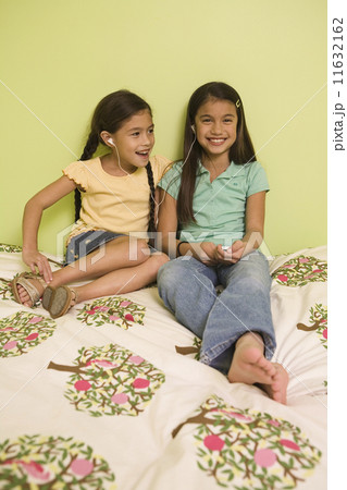 Pacific Islander sisters listening to mp3 player 11632162