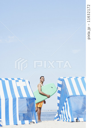 Hispanic man holding boogie board at beach Hispanic man holding boogie board at beach 11632172