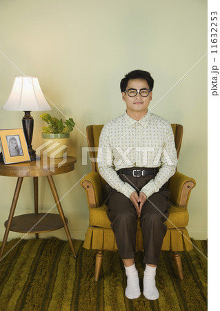 Nerdy Asian man sitting in armchair Nerdy Asian man sitting in armchair 11632253