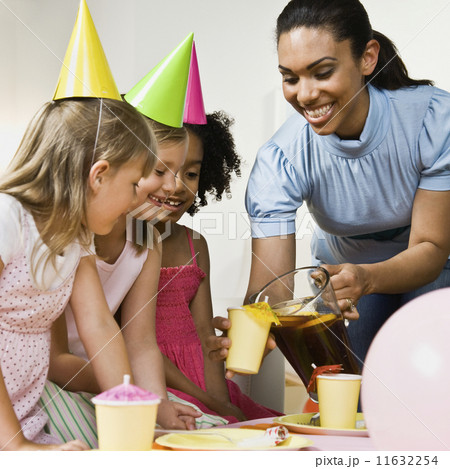 Mixed Race woman pouring drink at daughter's party 11632254