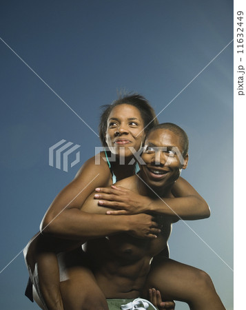 African American man giving girlfriend piggyback ride 11632449