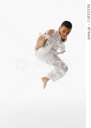 Studio shot of Hispanic boy performing martial arts kick 11632556