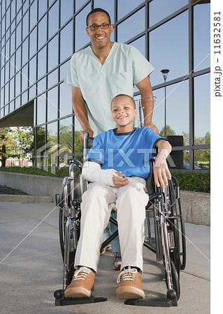 African boy in wheelchair with nurse in front of hospital 11632581