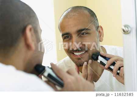 Middle Eastern man shaving with electric razor 11632585