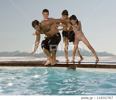 Hispanic children pushing father into swimming pool 11632767