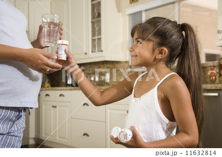 Hispanic girl handing medication to pregnant mother 11632814