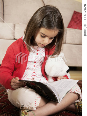 Middle Eastern girl reading on floor 11632820