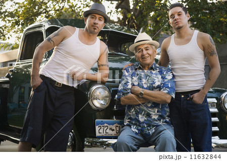 Hispanic father and adult sons in front of car Hispanic father and adult sons in front of car 11632844