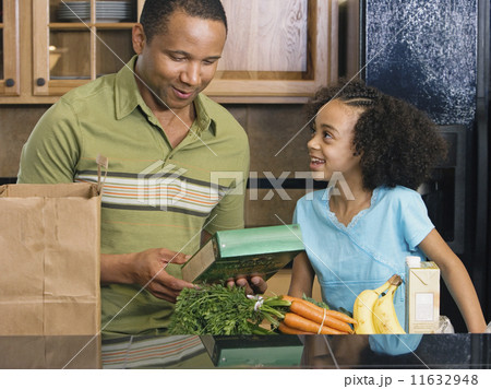 African father and daughter with groceries in kitchen African father and daughter with groceries in kitchen 11632948