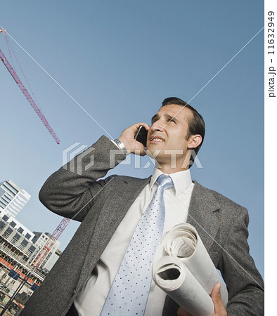 Hispanic businessman holding blueprints 11632949