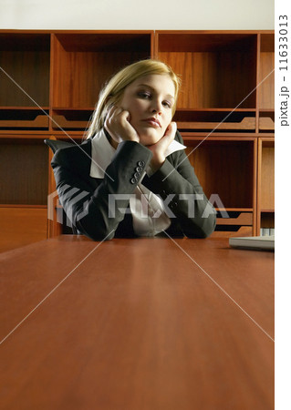 Young Hispanic businesswoman sitting at conference table leaning chin in hands 11633013