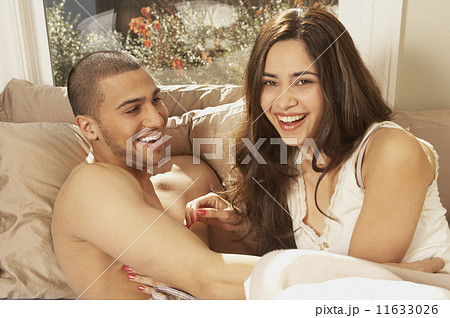 Hispanic couple laughing in bed  11633026