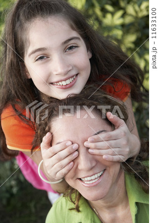 Hispanic girl covering mother's eyes Hispanic girl covering mother's eyes 11633100